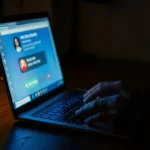 Person receiving an AI voice scam call on a laptop in a dark room — cybersecurity threats 2026