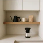 A close-up of a built-in wooden coffee station with an espresso machine, a bag of coffee beans, and a white mug on a shelf.