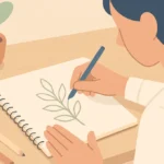 A person sitting at a table, sketching in a notebook with pencils, instead of looking at a phone.