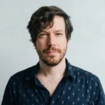 John Gallagher Jr. actor and musician performing on Broadway stage with acoustic guitar