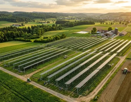 Aerial view of elevated solar panels installed above crop rows on a working farm, showing an agrivoltaic dual-use system