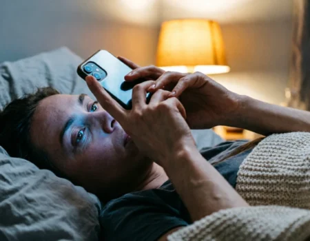 Person in bed at night scrolling phone, illustrating how to stop doomscrolling without quitting social media