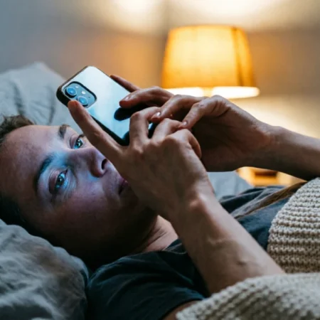 Person in bed at night scrolling phone, illustrating how to stop doomscrolling without quitting social media